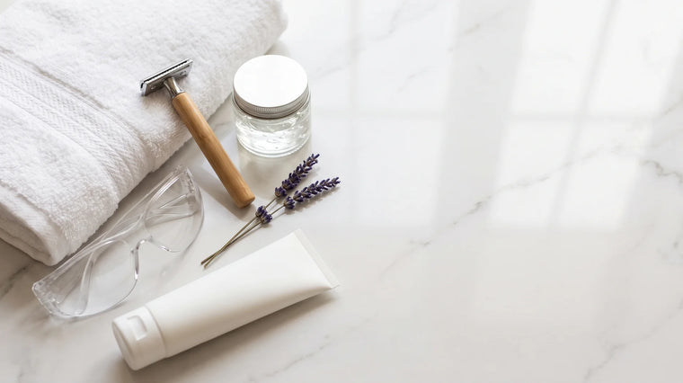 Mermer banyo tezgâhında havlu, jilet, aloe jeli, koruyucu gözlük ve güneş kremi